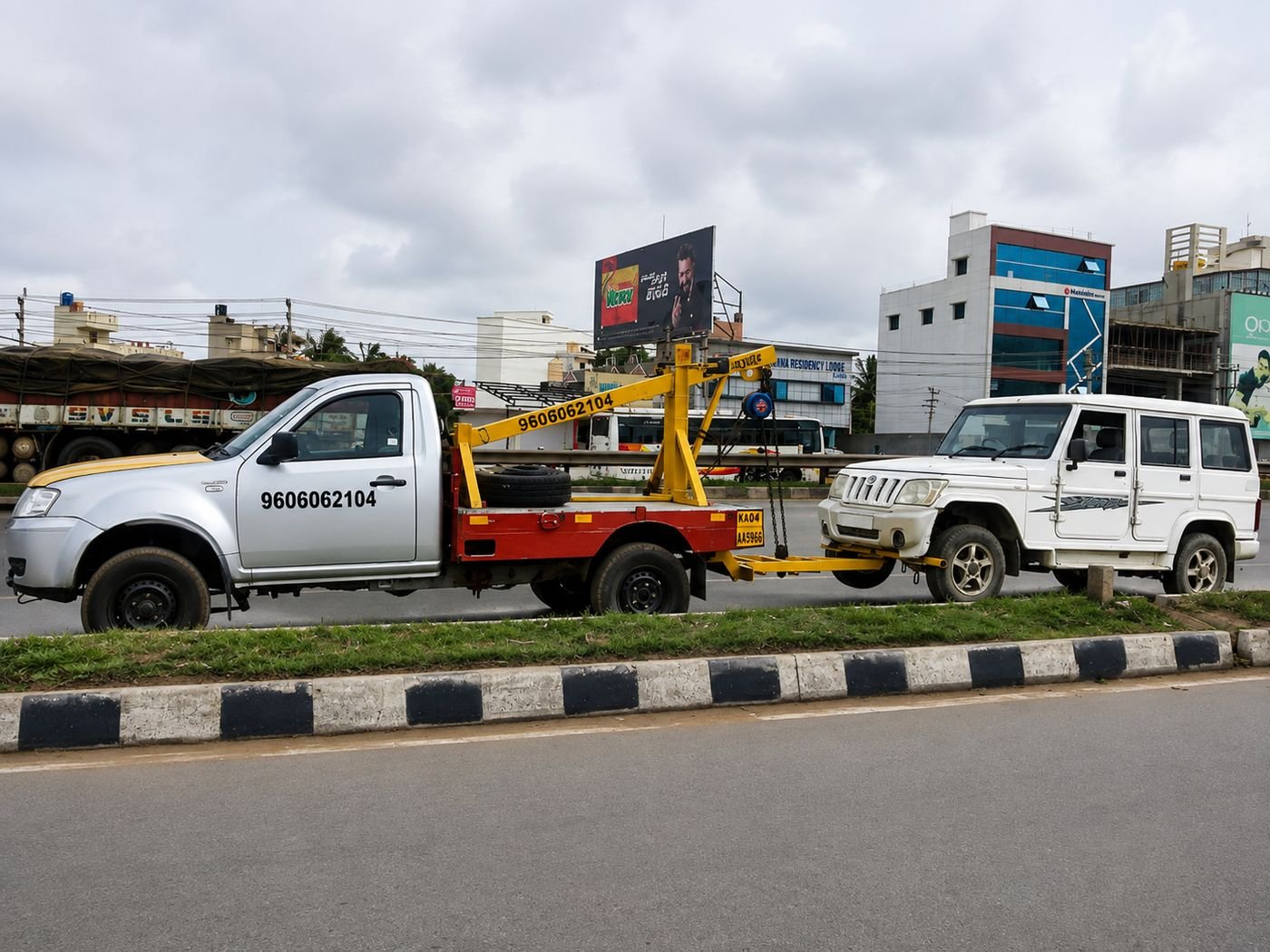 Ganesh Towing Service tow truck towing a Mahindra Bolero on a Bangalore main road